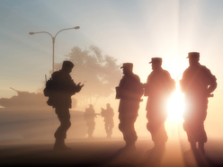 silhouettes during sunset of an army soldiers aligned next to each other and a commander in front of them