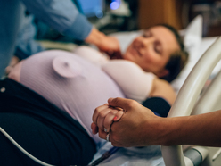 A woman in labor in the hospital holding her partner's hand