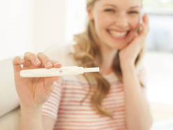 Woman smiling holding positive pregnancy test