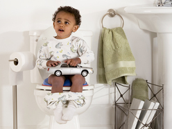 A toddler boy sitting on the toilet, potty training.