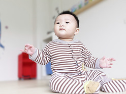 Baby sitting up in a onesie