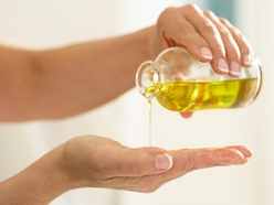 woman pouring oil from bottle onto palm