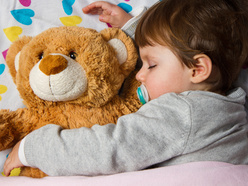 toddler boy sleeping in bed with his teddy bear