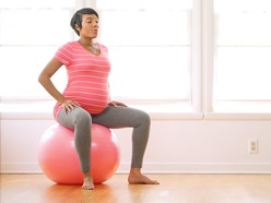 pregnant woman sitting on medicine ball