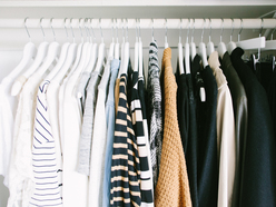 Long-sleeve women's shirts and pants hanging neatly in a closet