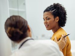 A woman talking to her healthcare provider in a doctor's office. 