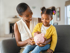 baby putting coins in piggy bank