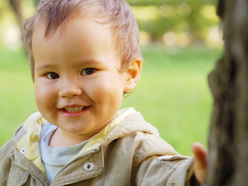 smiling boy standing near a tree