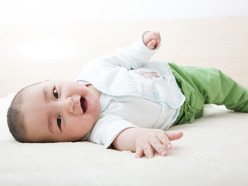 smiling baby on blanket trying to roll over