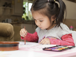 child sitting and doing watercolor painting