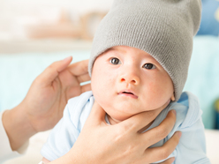 hands holding up a young babys head while being burped