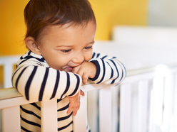 A toddler standing up in a crib.