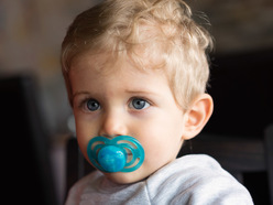 A toddler with a pacifier in his mouth