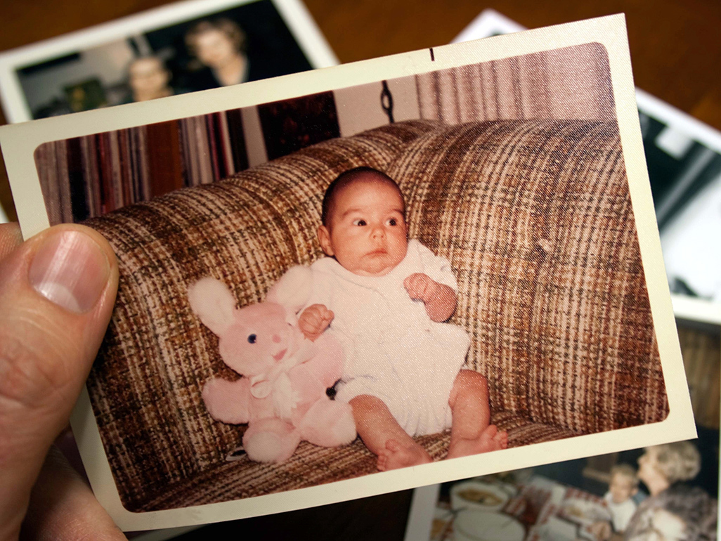 A Polaroid of a baby holding a stuffed animal's hand