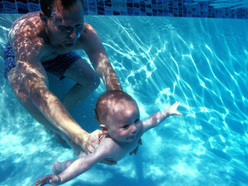 underwater shot of a young baby in a swimming pool with his dad