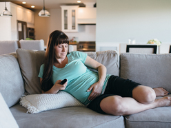 Pregnant woman on the sofa holding her bump