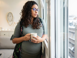 Pregnant woman holding a mug and looking out of the window