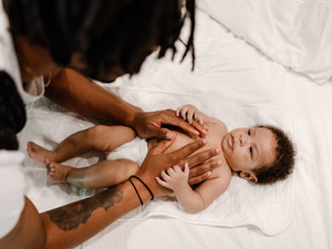 father putting his hands on baby's chest after a diaper change