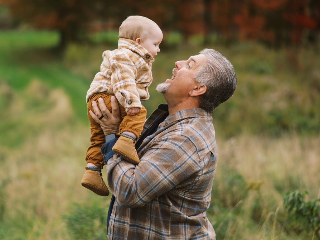 A man smiling at and holding a baby