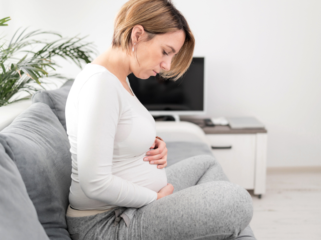 pregnant woman looking down at her belly