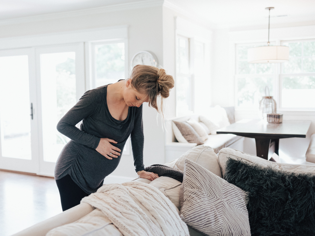 Pregnant woman in pain leaning on couch 