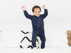 A happy toddler smiling and jumping on the bed.