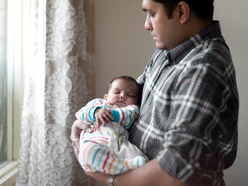 man cradling sleeping baby