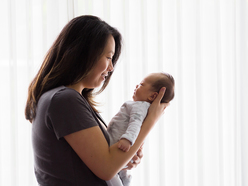 mom holding newborn as they look into each other's eyes