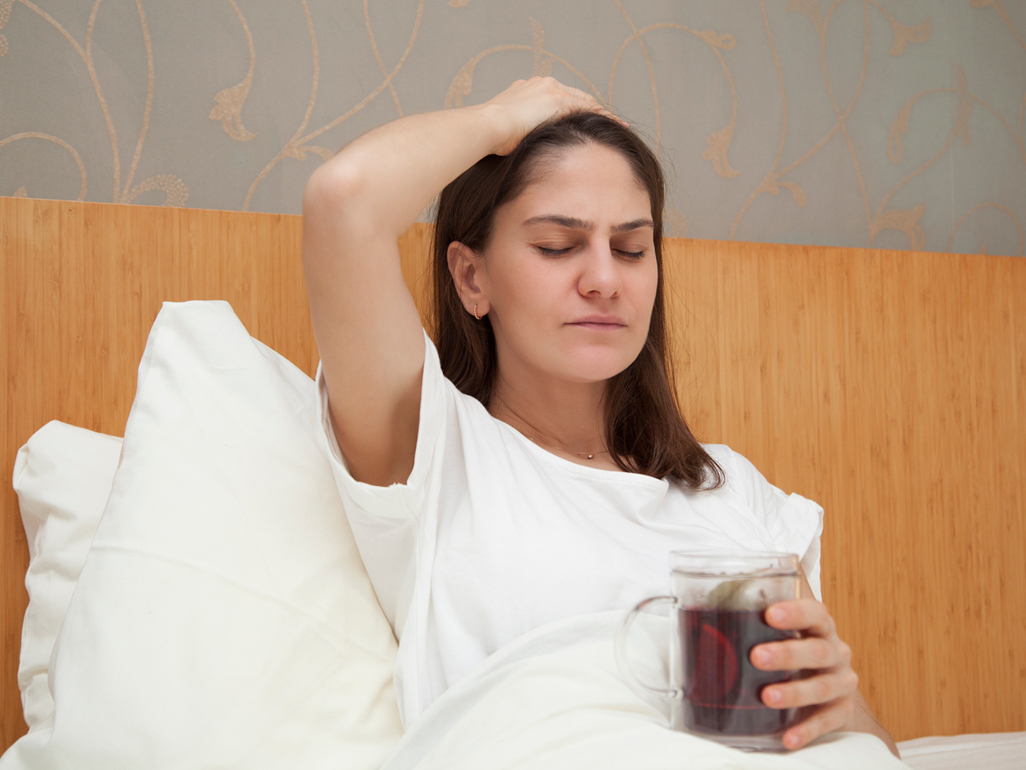 Pregnant woman sitting in bed feeling nauseous