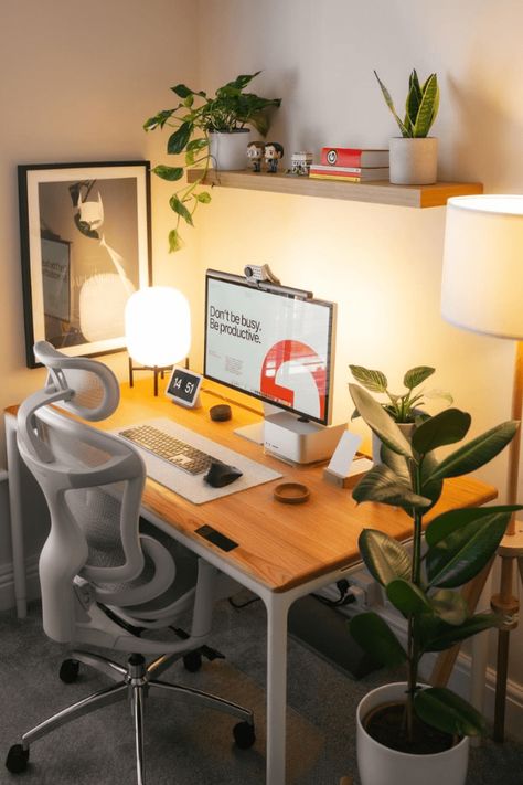 a desk with a computer, lamp and potted plant on it in an office