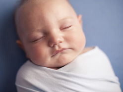 sleeping baby swaddled in white blanket