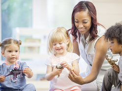 Preschool teacher sitting with three young children