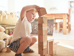 Two and a half year old boy building a tower with wooden blocks