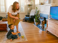 Mom putting television on for toddler in living room