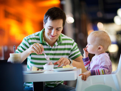 Vater beim Essen mit dem Baby im Hochstuhl