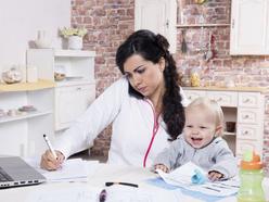 Mãe trabalha em casa no computador e cuidando do bebê